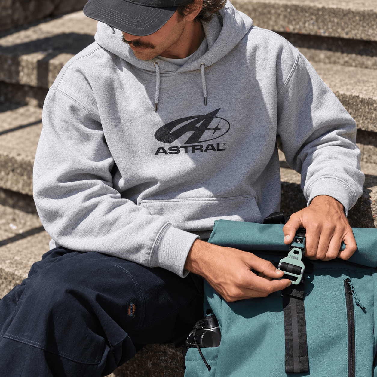 Chico con polera gris ASTRAL abriendo una mochila